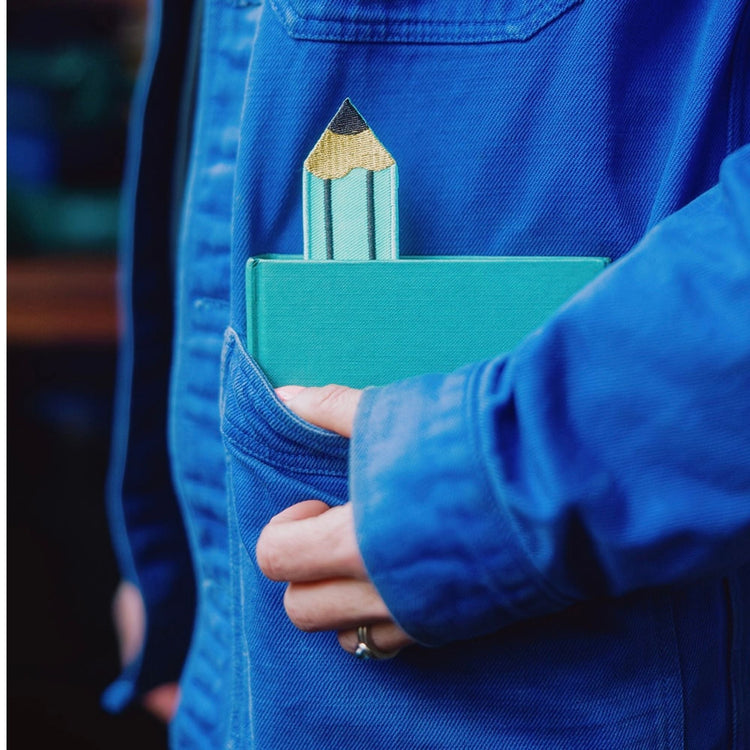 Retro Pencil Embroidered fabric bookmark in book in blue chore jacket.