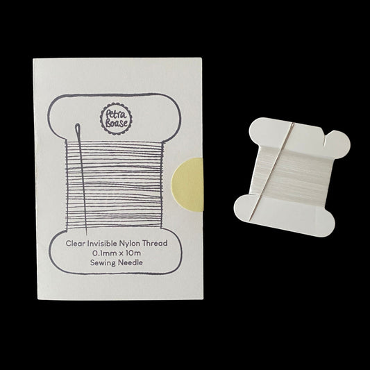 Clear invisible nylon thread spool with packaging on a white background