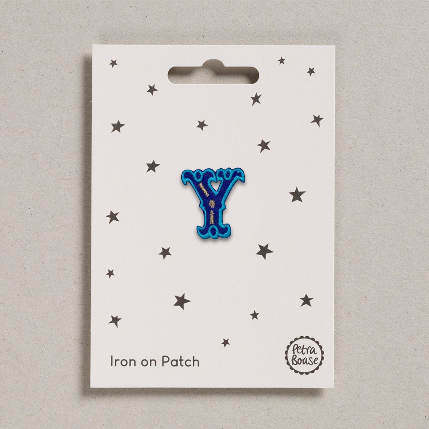 A blue embroidered letter 'Y' iron on patch with stars around it on a white background.