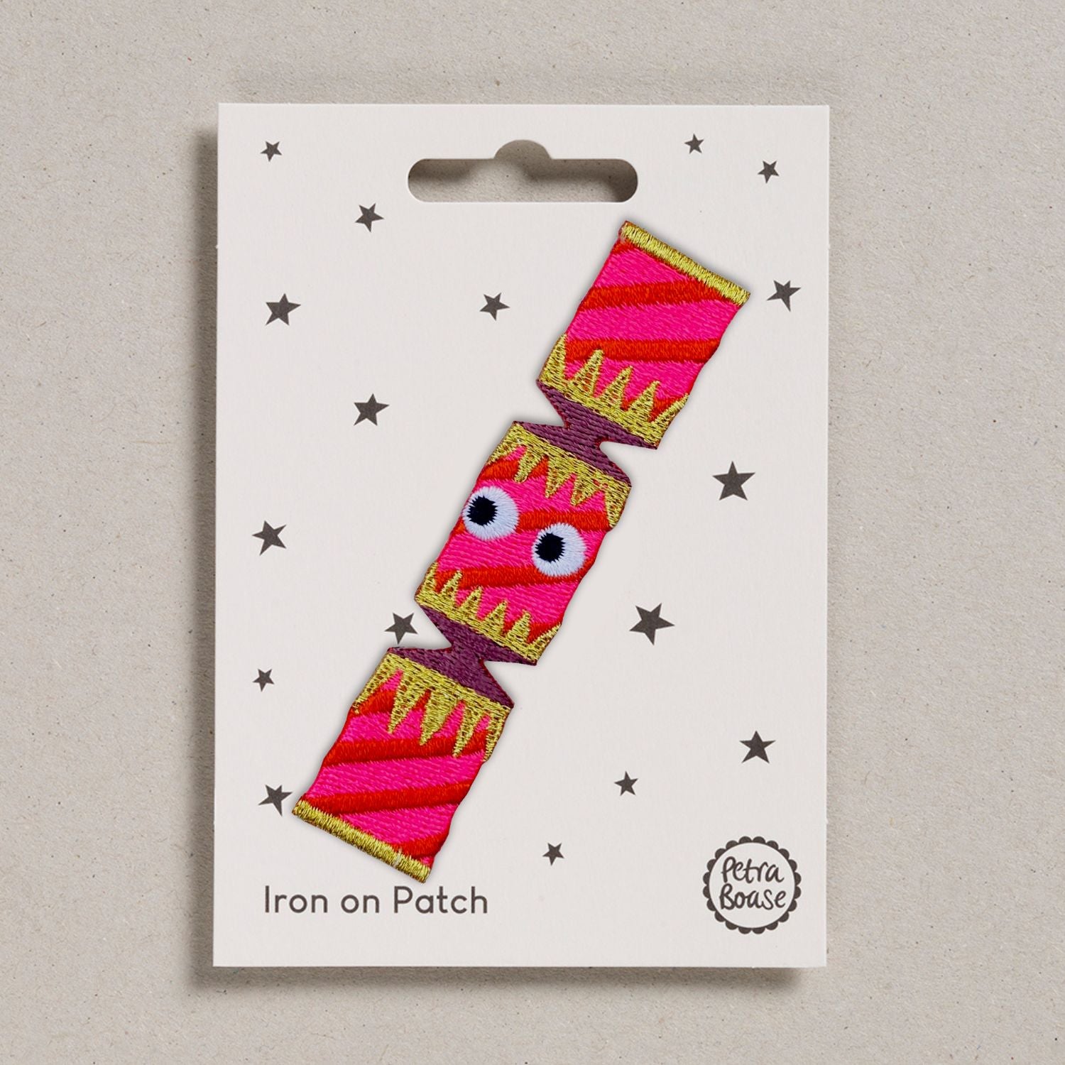 Fun Christmas cracker iron on patch. Red fabric with flouro pink and gold embroidery with fun googlyeye details. 