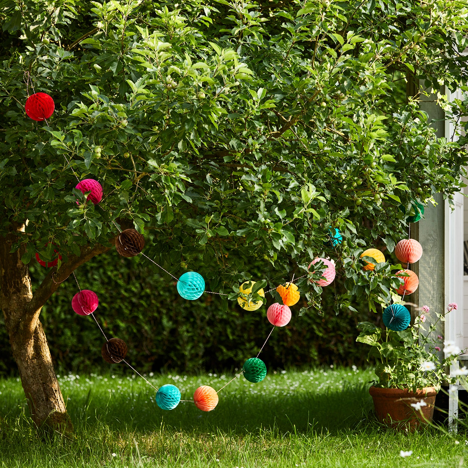 Colourful Eco paper ball garland garden party setting