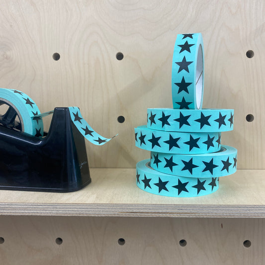 Turquoise Eco paper adhesive tape with black star print on a shelf.